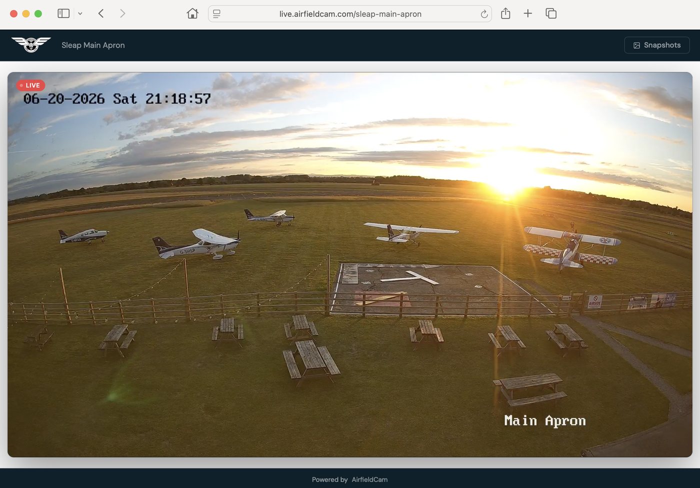 The AirfieldCam public viewer page at live.airfieldcam.com/sleap-main-apron, showing Sleap airfield at sunset with aircraft on the apron